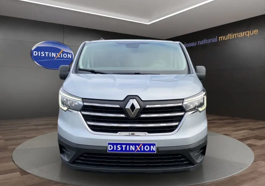 Vue frontale d'un Renault Trafic Combi gris platine 2023 avec calandre chromée et logo Renault bien visible.