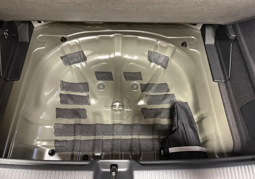 Coffre ouvert d’un Audi Q2 35 TFSI S Line 2026 montrant le logement métallique de la roue de secours sans pneu.