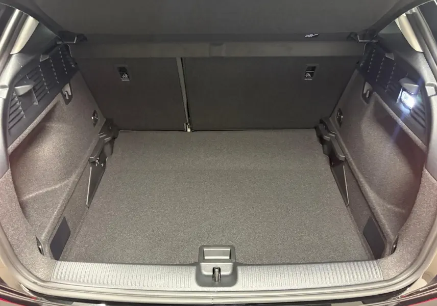 Coffre ouvert vu de l'arrière d'un Audi Q2 Noir Mythic, montrant un espace de chargement propre et bien éclairé.