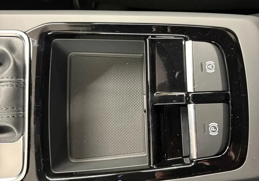 Vue rapprochée de la console centrale noire avec commandes de frein de parking et rangement, intérieur Audi Q2 2026.