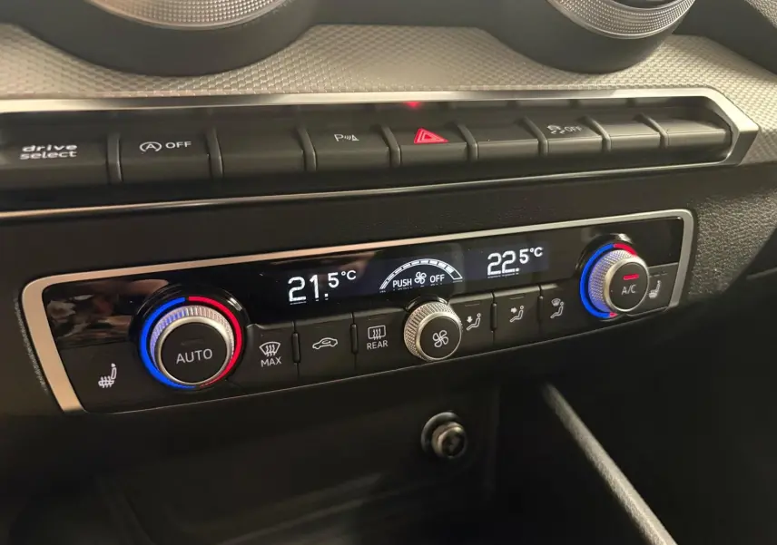 Gros plan sur la console de climatisation automatique de l'Audi Q2 35 TFSI S Line avec réglages digitaux et boutons rétroéclairés.