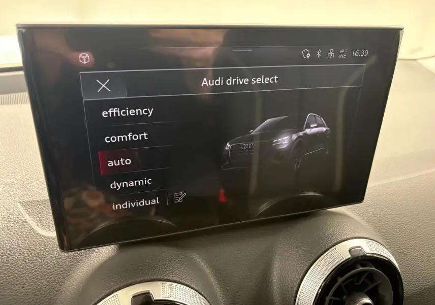Écran central de l'Audi Q2 35 TFSI S Line 2026 affichant les modes de conduite avec une vue stylisée du SUV noir Mythic.