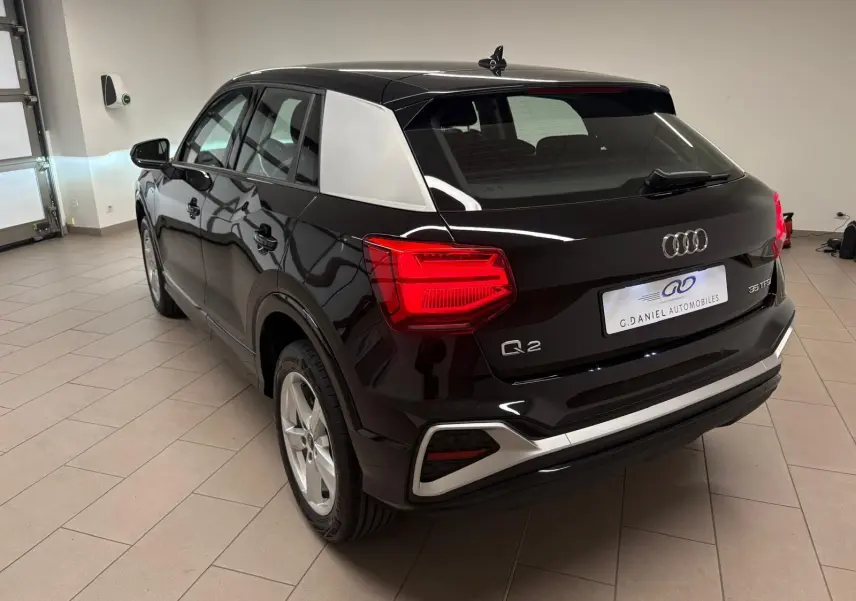 Audi Q2 35 TFSI S Line noir mythic vu en 3/4 arrière droit, avec toit et montant arrière contrastés argentés.