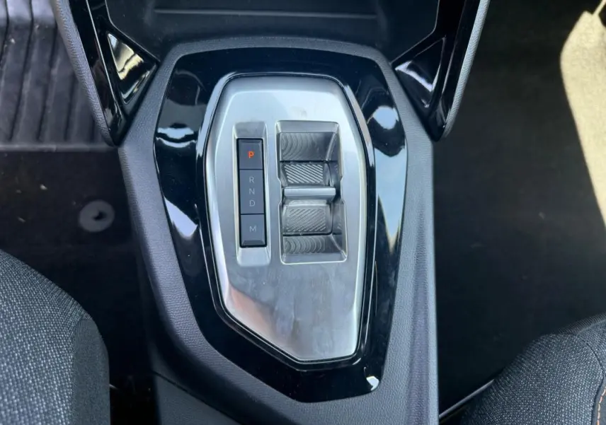 Vue plongeante sur la console centrale du Peugeot 2008 Hybrid noir, montrant la commande de boîte automatique compacte.