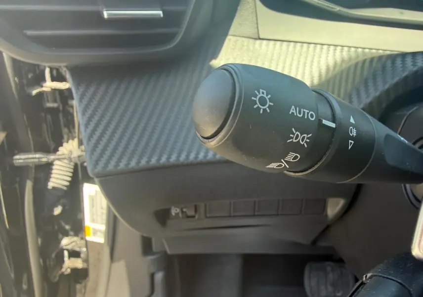 Gros plan sur la commande d’éclairage du tableau de bord du Peugeot 2008 Hybrid 136 e-DCS6 Style noir, intérieur carbone.