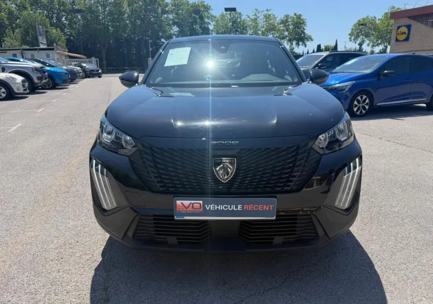 Vue frontale d'un Peugeot 2008 Hybrid noir 2025 avec calandre noire et feux LED verticaux distinctifs.