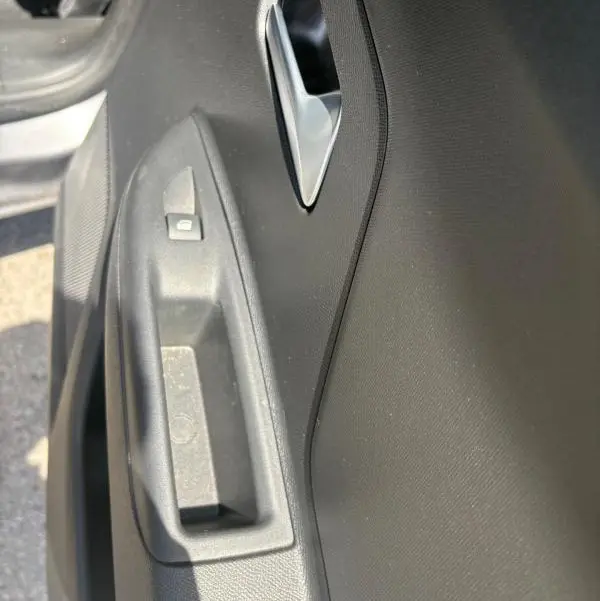 Gros plan sur la poignée intérieure et le bouton de verrouillage de la porte côté conducteur d'une Opel Mokka électrique gris 2025.