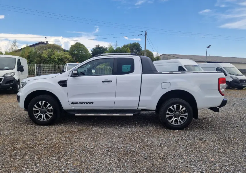 Vue de profil côté gauche d'un Ford Ranger Wildtrak blanc avec cabine allongée et marchepied visible.