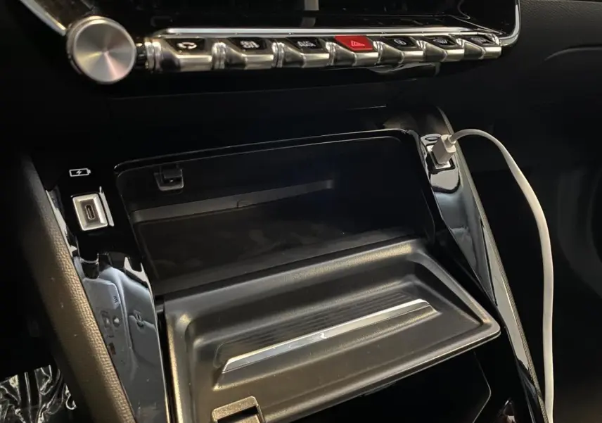 Détail de la console centrale du Peugeot 2008 e-136 Allure Pack 2022 avec prise USB et câble de recharge connecté.
