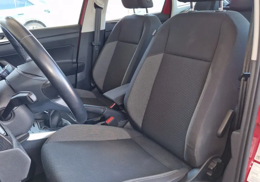 Vue intérieure côté conducteur du Volkswagen Taigo rouge roi 2023, sièges noirs en tissu et volant visible.