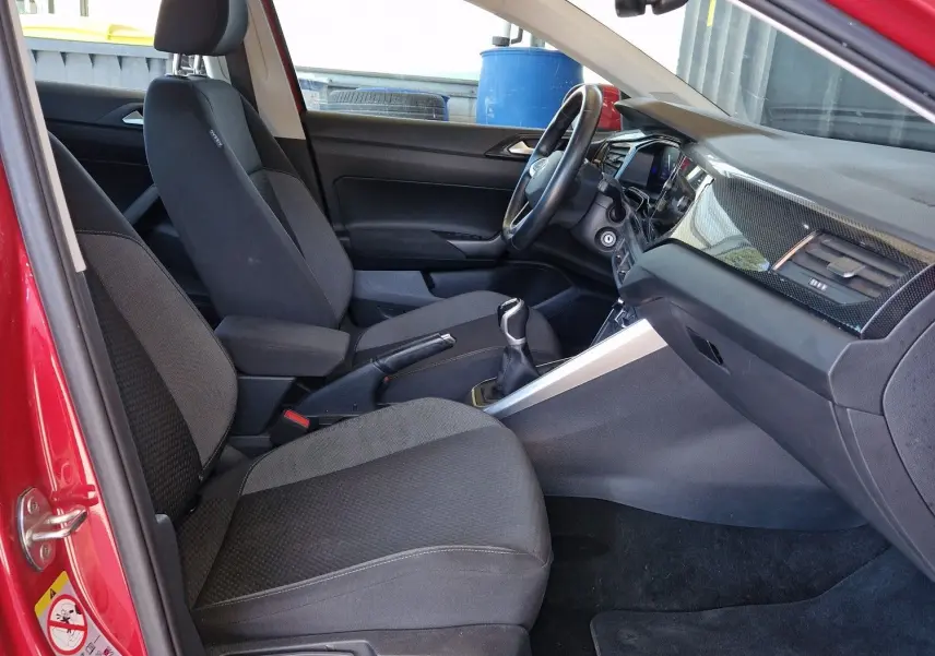Intérieur côté conducteur du Volkswagen Taigo rouge roi 2023, avec sièges noirs et tableau de bord moderne.