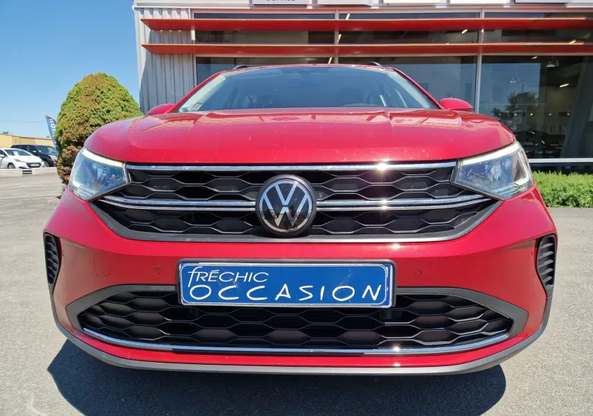Vue frontale d'un Volkswagen Taigo rouge roi 2023 avec calandre noire et plaque d'occasion bleue.