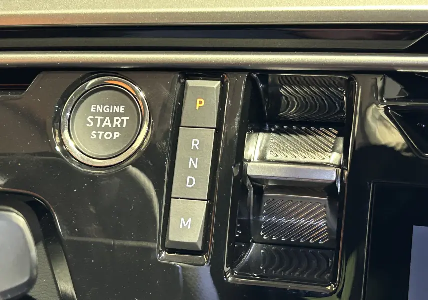Gros plan sur la console centrale noire brillante avec bouton start/stop et commandes de boîte automatique du Peugeot 5008 bleu Ingaro.