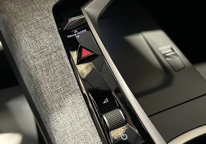 Gros plan sur la console centrale intérieure du Peugeot 5008 III Hybrid, montrant les boutons Drive Mode et warning.