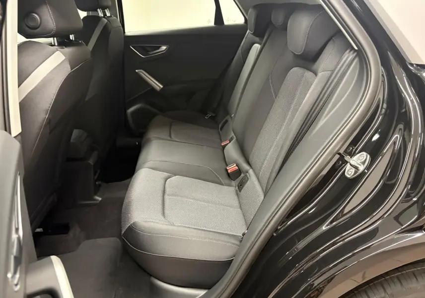 Vue intérieure côté gauche des sièges arrière en tissu gris du SUV Audi Q2 35 TFSI S Line noir mythic, porte arrière ouverte.