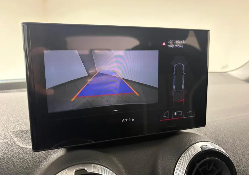 Écran central affichant la caméra de recul et l'alerte de trajectoire dans l'Audi Q2 Noir Mythic, vue intérieure.