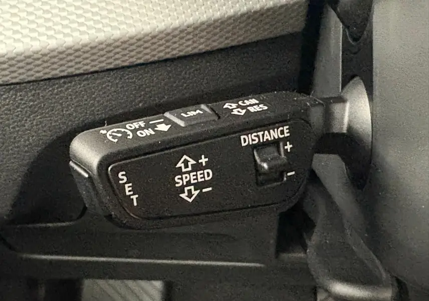 Gros plan sur la commande de régulateur de vitesse adaptatif dans l’habitacle d’un Audi Q2 noir Mythic.