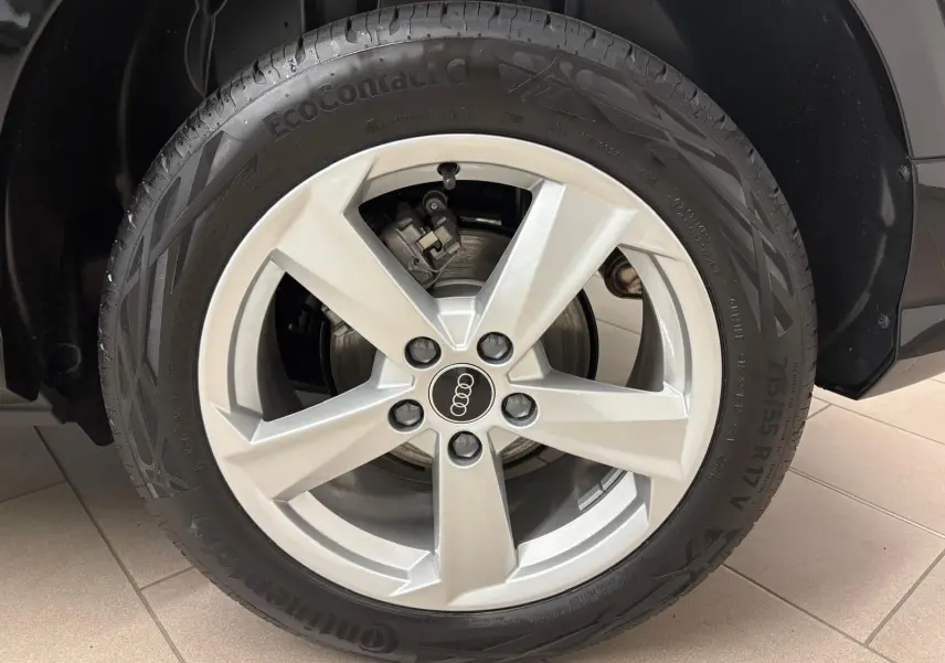 Gros plan sur la roue avant gauche de l'Audi Q2 35 TFSI S Line 2026 en Noir Mythic avec jante argentée cinq branches.