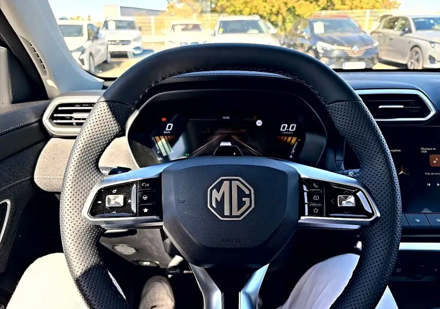 Vue centrée sur le volant noir perforé du MG ZS 1.5 hybrid 197 avec tableau de bord numérique et écran tactile visible.