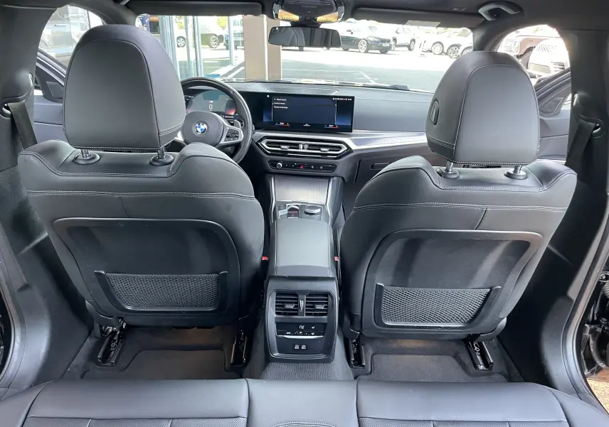 Vue arrière de l'intérieur d'une BMW Série 3 Touring G21 noir métal, avec sièges cuir noir et tableau de bord moderne.
