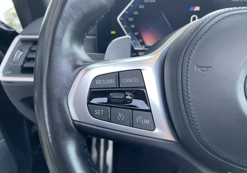 Gros plan sur les commandes de régulateur de vitesse au volant cuir noir d'une BMW Série 3 Touring G21 2022.