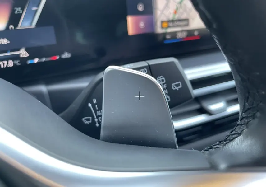 Gros plan sur la palette de changement de vitesse droite en aluminium brossé dans le volant cuir noir d'une BMW Série 3 Touring G21.