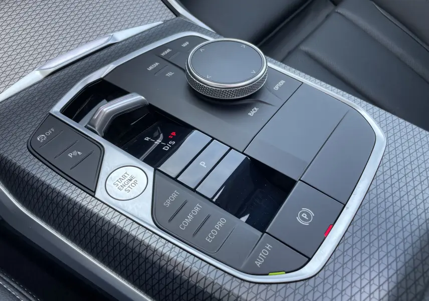 Gros plan sur la console centrale noire de la BMW Série 3 Touring G21 XDrive 190 M Sport avec commandes de boîte auto et modes de conduite.