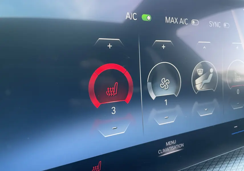 Gros plan sur l'écran tactile de la climatisation de la BMW Série 3 Touring G21 noir métal, affichant le chauffage de siège au niveau 3.