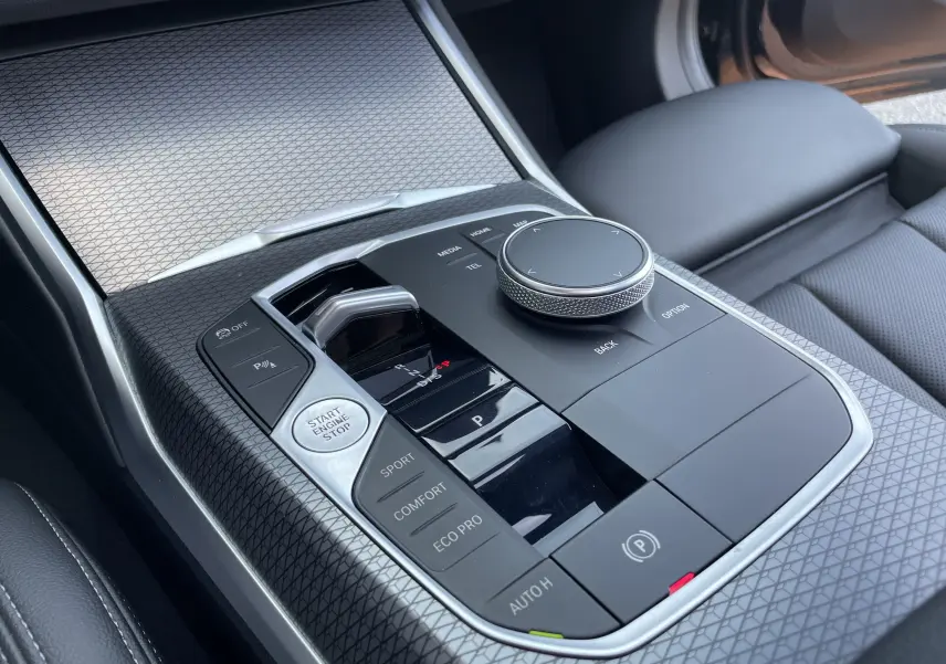 Gros plan sur la console centrale noire avec commandes de boîte auto et molette de contrôle du BMW Série 3 Touring G21.