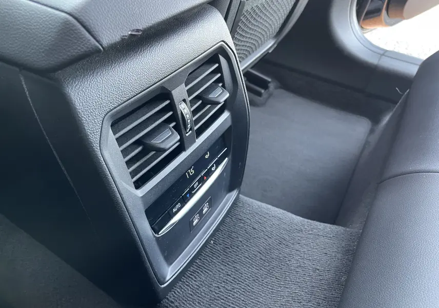 Détail de la console arrière noire avec commandes de climatisation et bouches d'aération dans une BMW Série 3 Touring G21 2022.