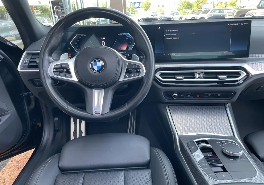 Vue intérieure avant de la BMW Série 3 Touring G21 M Sport 2022, tableau de bord numérique et volant cuir noir.