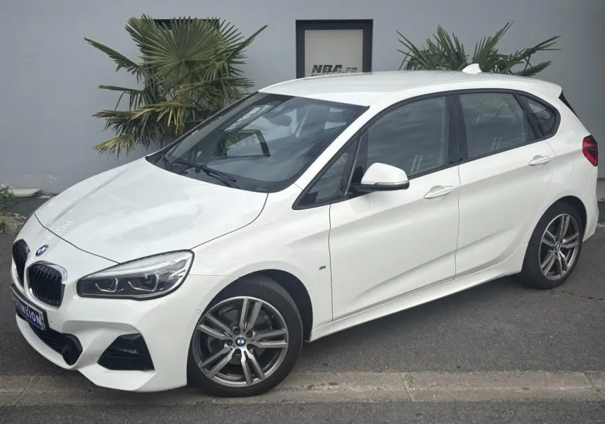 BMW Série 2 Active Tourer 218dA blanc vue 3/4 avant droit avec jantes alliage 18 pouces et hayon électrique.