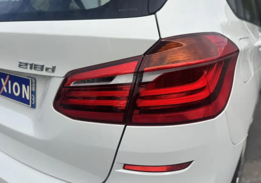 Gros plan sur le feu arrière droit d’une BMW Série 2 Active Tourer 218d blanche, avec badge moteur visible.