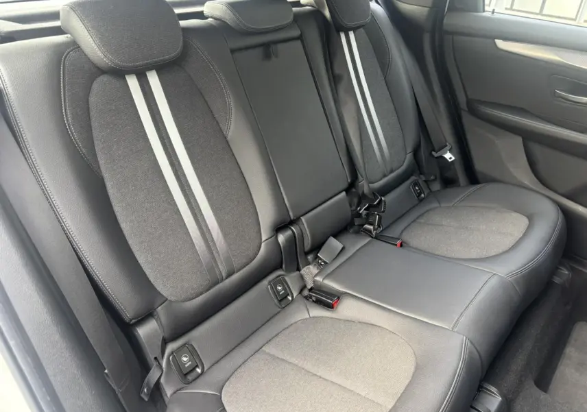 Vue intérieure côté droit des sièges arrière gris foncé avec bandes claires au centre dans une BMW Série 2 Active Tourer blanche.