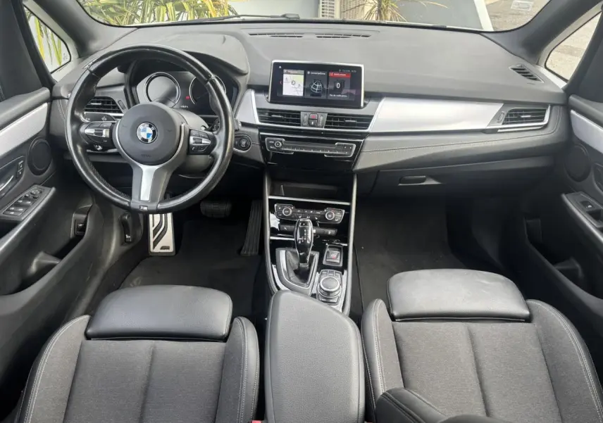 Vue intérieure avant de la BMW Série 2 Active Tourer 218dA 2020, tableau de bord noir avec écran GPS central et volant cuir M.