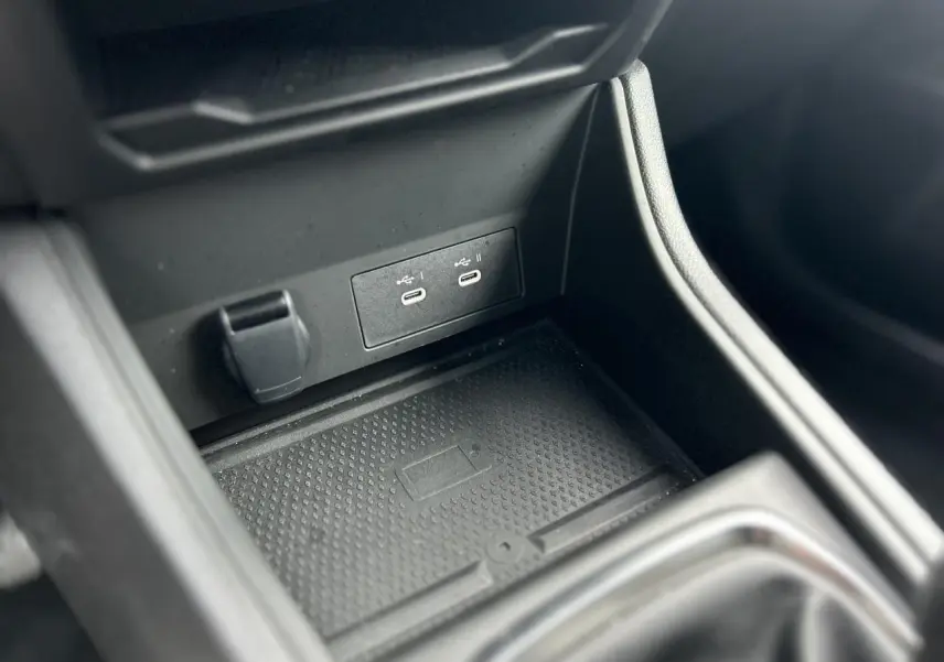 Gros plan sur la console centrale noire du Renault Captur 2025, montrant les ports USB-C et la zone de charge sans fil.