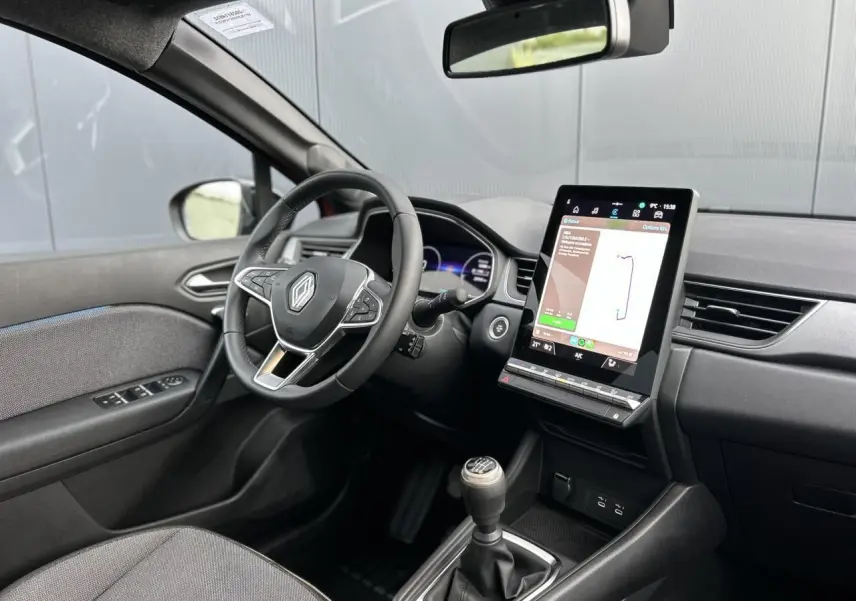 Intérieur Renault Captur 2025 vu côté conducteur, tableau de bord noir avec écran tactile vertical et boîte manuelle.