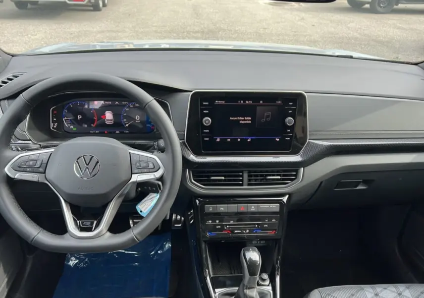 Vue intérieure du tableau de bord et volant cuir multifonctions d'un Volkswagen T-Cross gris argent 2025, avec écran tactile central.