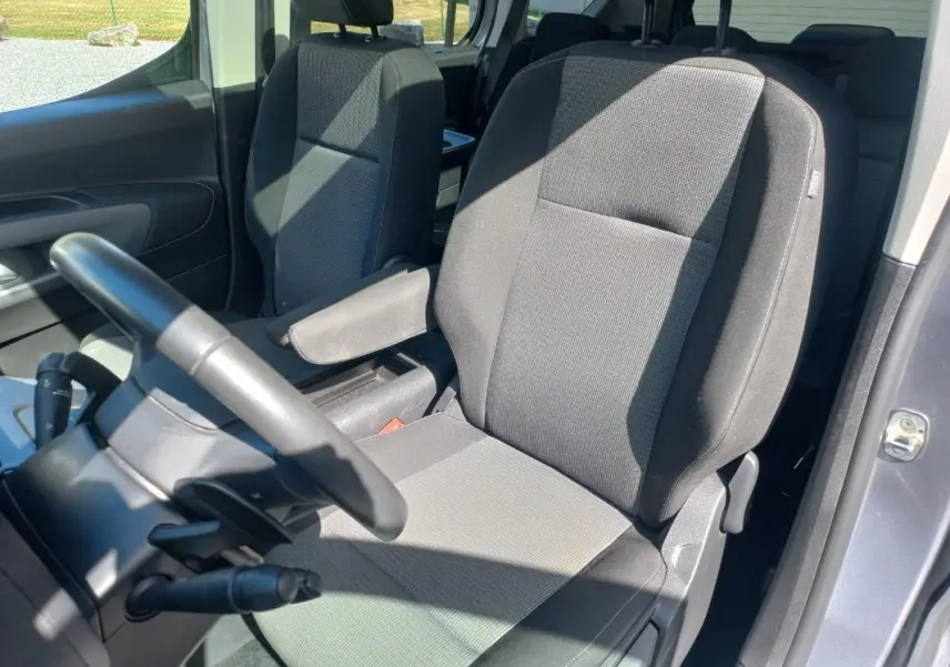 Vue intérieure côté conducteur du Toyota Proace City Verso gris 2023, mettant en valeur le siège tissu et l'accoudoir.