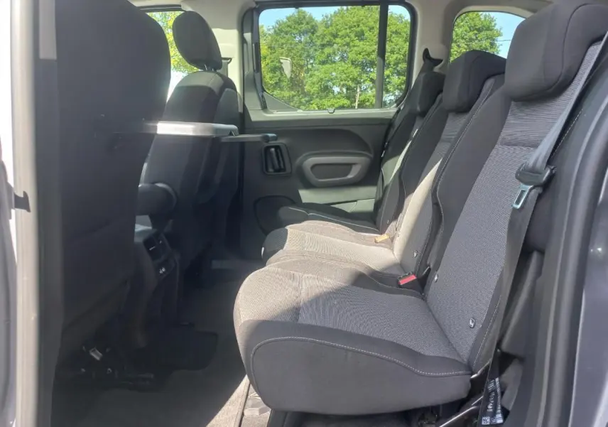 Vue latérale intérieure côté droit du Toyota Proace City Verso gris 2023, montrant la banquette arrière et une tablette rabattable.