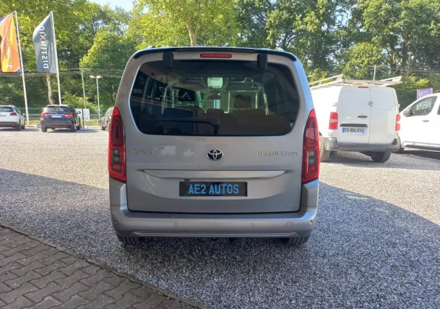 Vue arrière d'un Toyota Proace City Verso gris 2023, avec vitres teintées et plaque AE2 AUTOS visible.