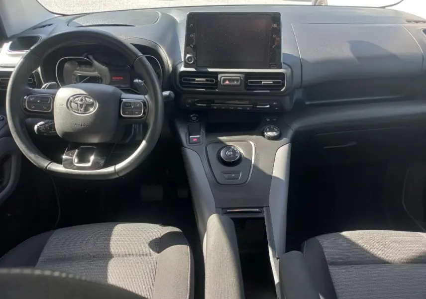 Vue intérieure avant du Toyota Proace City Verso gris 2023, mettant en valeur le tableau de bord et le volant multifonction.