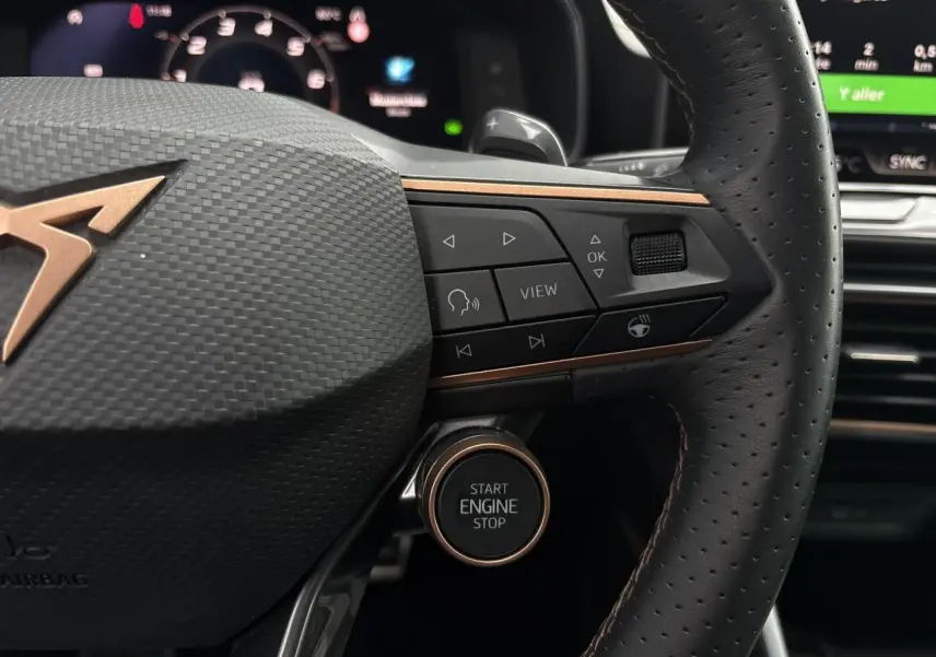 Gros plan sur le volant cuir perforé noir avec logo CUPRA cuivré et bouton start/stop du Leon ST Gris Graphene 2025.