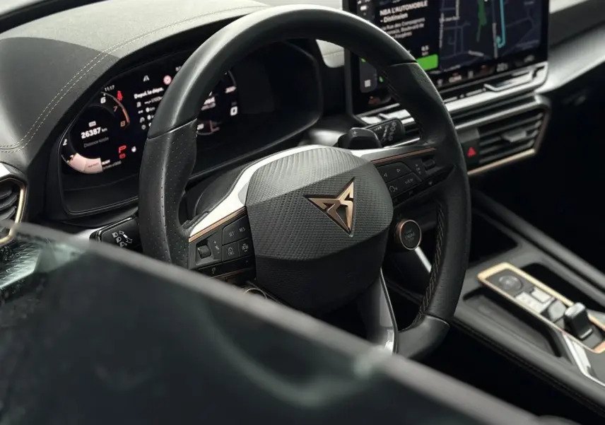 Vue rapprochée du volant cuir noir perforé avec logo CUPRA et tableau de bord digital du Leon ST Gris Graphene 2025.