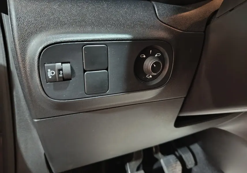 Vue rapprochée des commandes de réglage des phares et des rétroviseurs côté conducteur dans un intérieur noir de Citroën C3 gris foncé.