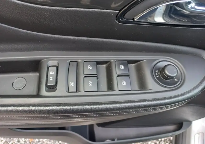 Gros plan sur les commandes des vitres et rétroviseurs côté conducteur d’un Opel Mokka X gris, intérieur noir.