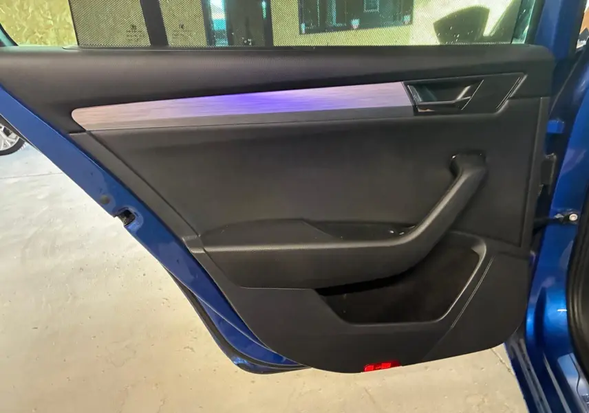 Vue rapprochée de la porte arrière gauche bleu métallisé d’une Skoda Superb Combi avec garniture intérieure noire et insert décoratif gris.