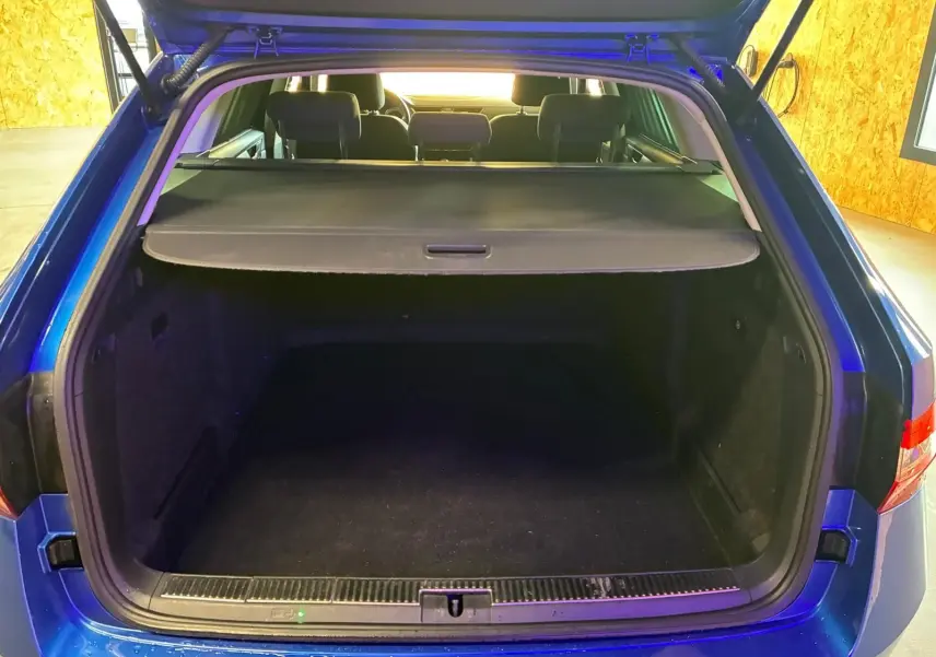 Coffre ouvert vu de l'arrière d'une Skoda Superb Combi bleu 2021, montrant l'espace de chargement et la tablette cache-bagages.