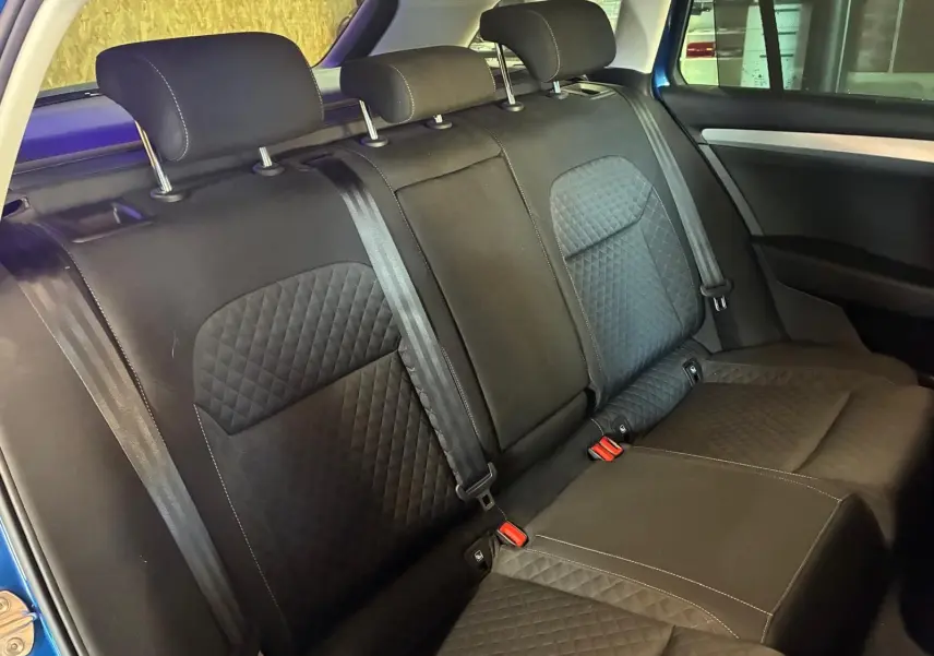 Vue intérieure de la banquette arrière noire en tissu matelassé du Skoda Superb Combi bleu, avec ceintures et appuie-têtes.