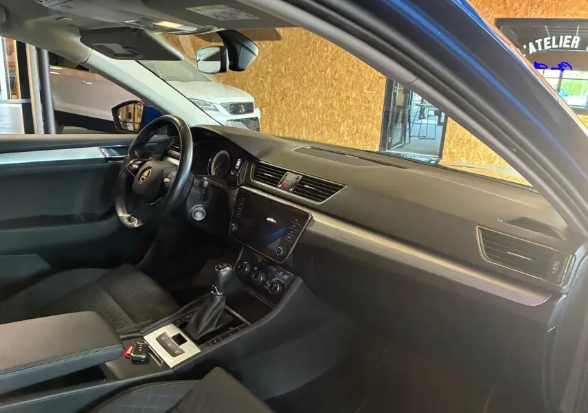 Vue intérieure côté conducteur du Skoda Superb Combi bleu 2021, avec tableau de bord moderne et volant multifonction.